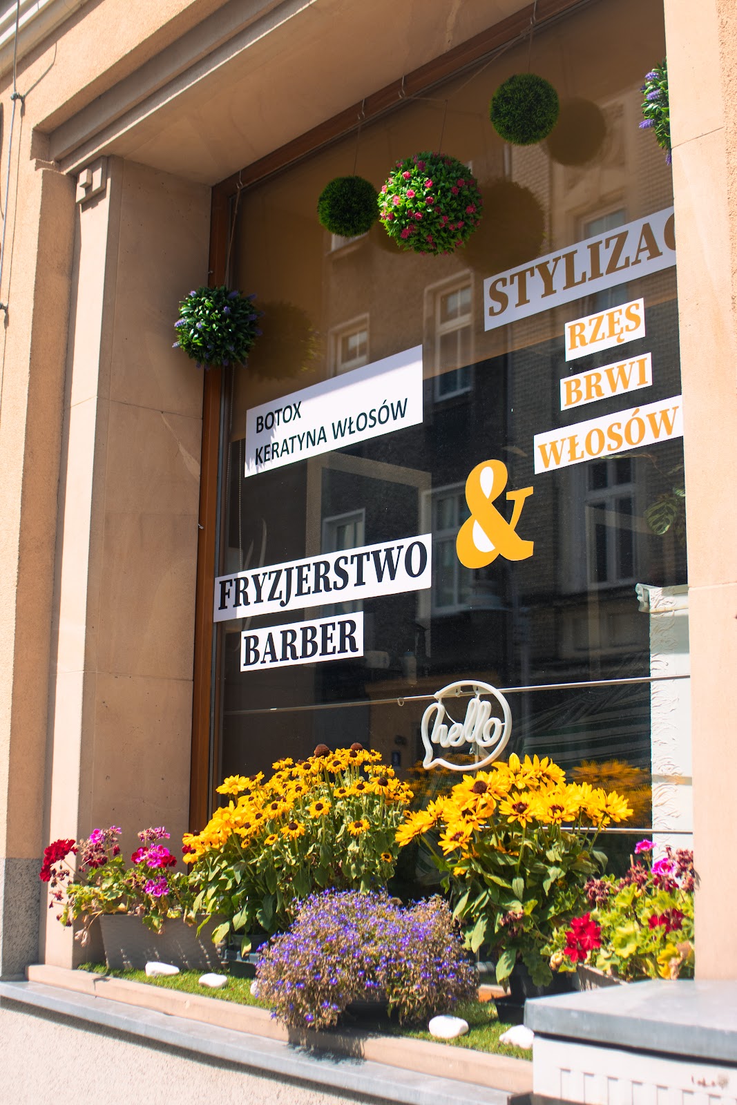 Witryna akademii z kwiatami i napisami o stylizacji rzęs, brwi i włosów